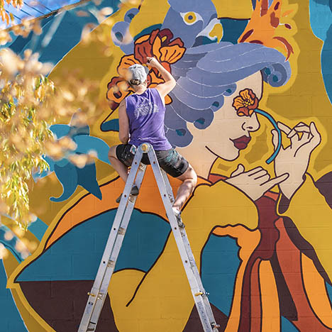 Sarah Slaughter works on a mural at the Sunalta Community Wildflower Garden